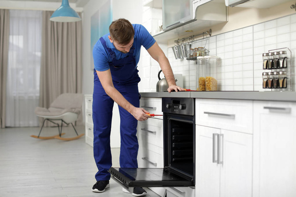 Profissional serviceman reparar forno moderno na cozinha
 - Foto, Imagem