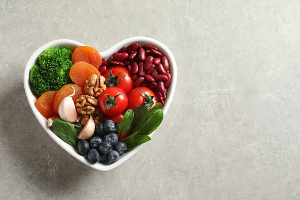 Bowl with heart-healthy diet products on grey background, top view. Space for text - Fotó, kép