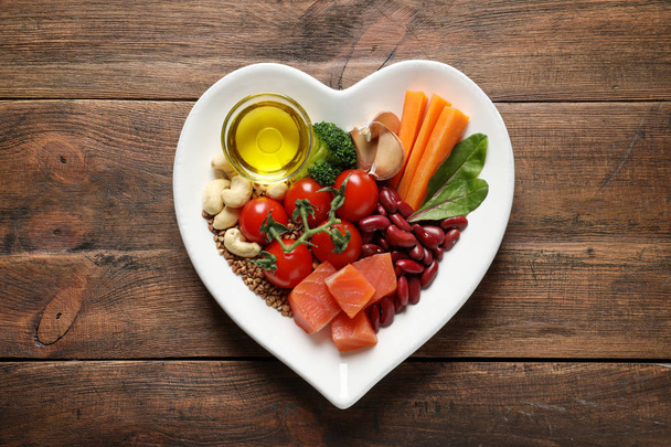 Plate with products for heart-healthy diet on wooden background - Fotó, kép