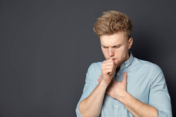 Handsome young man coughing against dark background. Space for text - Foto, immagini