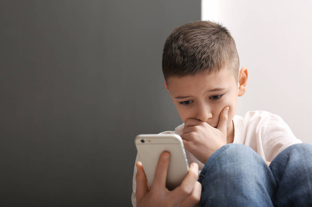 Upset boy with smartphone indoors. Space for text - Fotoğraf, Görsel