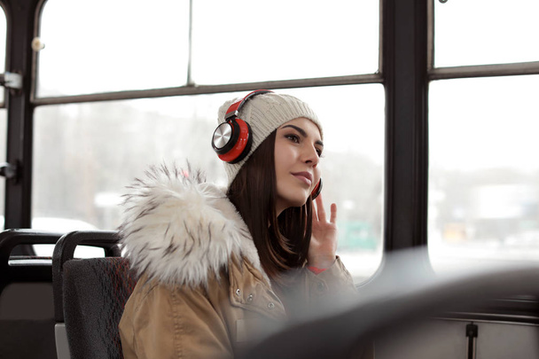Young woman listening to music with headphones in public transport - Valokuva, kuva