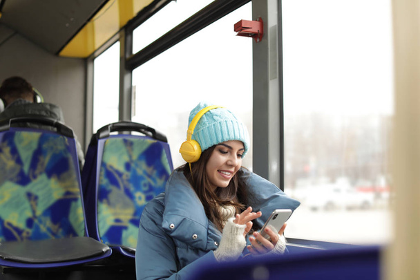 Young woman listening to music with headphones in public transport - Foto, imagen