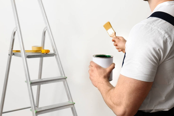 Male decorator with brush and paint can indoors, closeup. Space for text - Foto, immagini