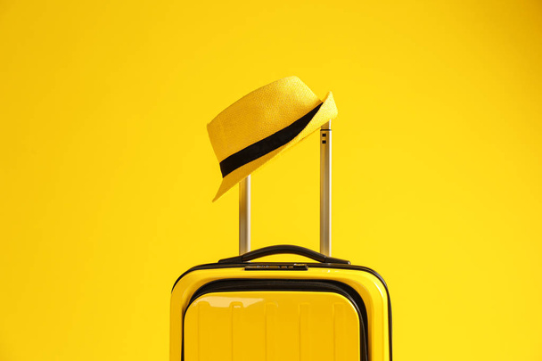 Bright suitcase with hat on color background - Zdjęcie, obraz