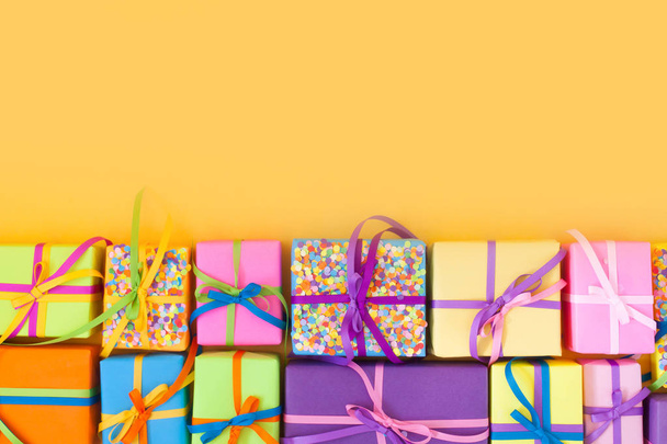 Colored gift boxes with colorful ribbons. Yellow background. Gifts for Christmas or a birthday. - Fotó, kép