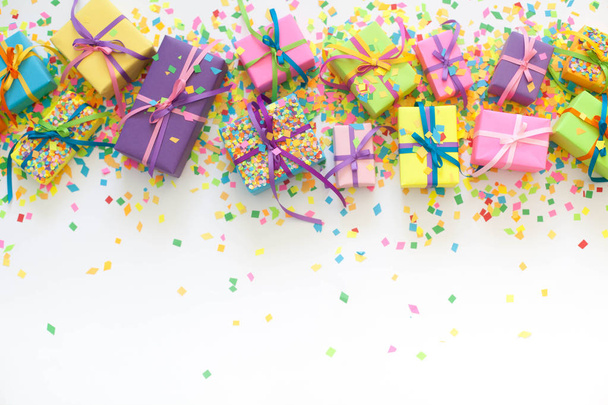 Colored gift boxes with colorful ribbons and confetti. White background. Gifts for Christmas or a birthday. - Fotó, kép