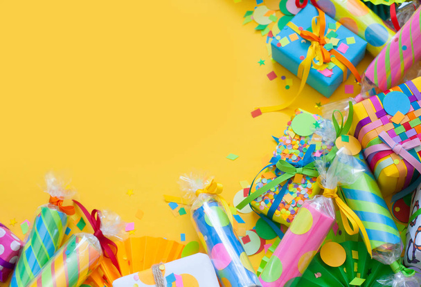 Celebratory crackers with confetti and bright gifts on a yellow background. - Photo, image