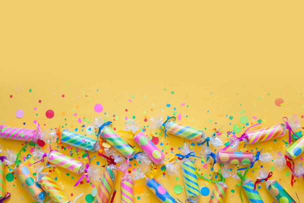 Celebratory crackers with confetti on a yellow background - Foto, Imagen