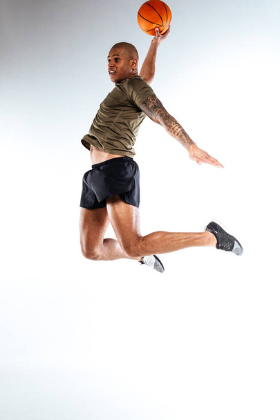 Basketball player jumping high holding a ball - Foto, afbeelding