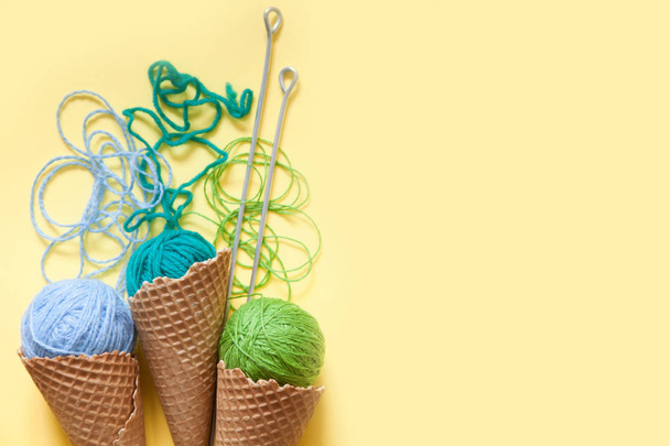 Balls of yarn lie in a waffle cone for ice cream. Coloured wool. - Φωτογραφία, εικόνα