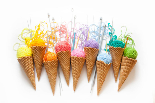 Balls of yarn lie in a waffle cone for ice cream. Coloured wool. - Zdjęcie, obraz
