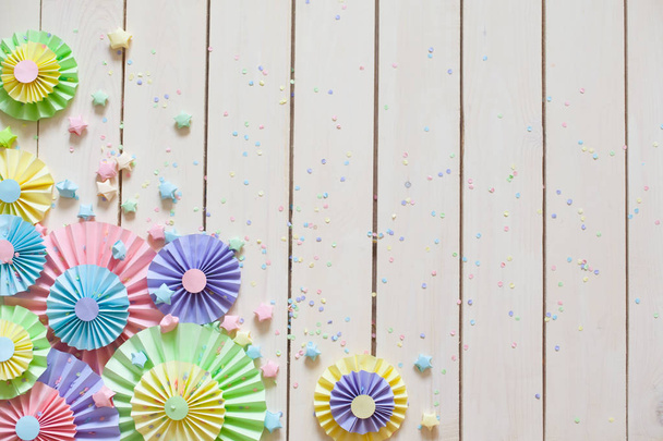 Colorful bright pastel paper rosette. Decorating for a party. White wood background - Fotó, kép