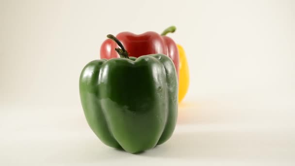 πράσινες, κίτρινες και κόκκινες πιπεριές κατά κουκλίτσα λευκό - γραμμή ρύθμιση - αριστερά - Πλάνα, βίντεο