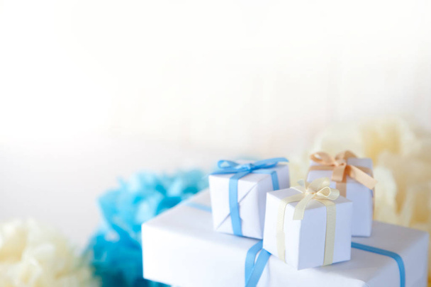 White gifts box with a blue, yellow and beige ribbons on the whi - 写真・画像