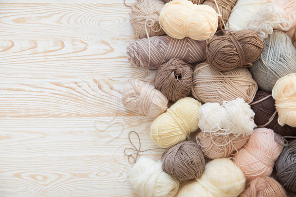 The yarn is beige, brown, gray and white. The background is aged wood. Knitting needles, scissors, coffee, knitting, knitted fabric. - Фото, зображення