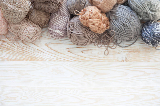 The yarn is beige, brown, gray and white. The background is aged wood. Knitting needles, scissors, coffee, knitting, knitted fabric. - Photo, image