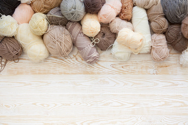 The yarn is beige, brown, gray and white. The background is aged wood. Knitting needles, scissors, coffee, knitting, knitted fabric. - Valokuva, kuva