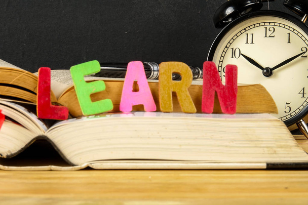 Концепція освіти з книгами, будильник, скло зі словом LEARN
. - Фото, зображення