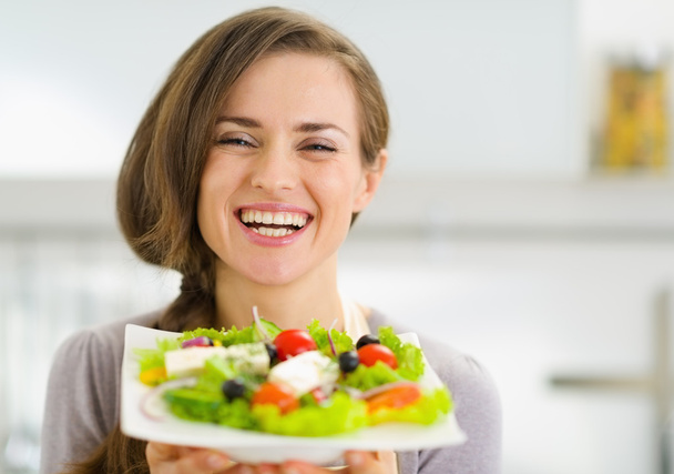 Smiling young woman showing fresh salad - Fotó, kép