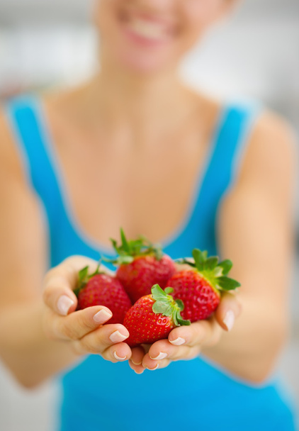 Closeup on smiling young woman giving strawberries - Фото, изображение