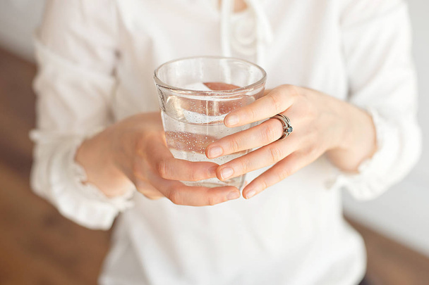 Close-up of a woman's hand holding a cold glass of water and ice over a white background - Valokuva, kuva