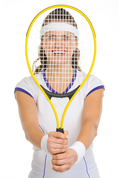 Smiling female tennis player looking through racket - Fotografie, Obrázek