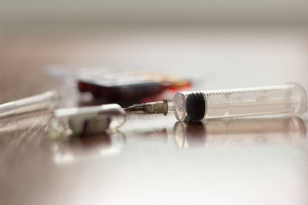 a used syringe and empty vial on the table - Photo, Image