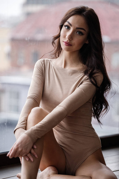 Studio muotokuva kaunis brunette nainen yllään beige vaatteita. Viehättävä kauneus malli poseeraa asunnoissa sisustus
   - Valokuva, kuva
