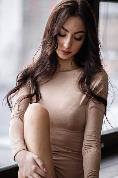 Studio portrait of beautiful brunette woman wearing beige clothes. Charming beauty model posing at apartments interior   - Foto, Imagem