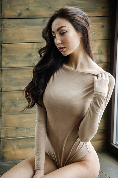 Studio portrait of beautiful brunette woman wearing beige clothes. Charming beauty model posing at apartments interior   - 写真・画像