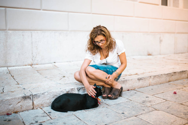 Woman playing with a cat on the street - Zdjęcie, obraz