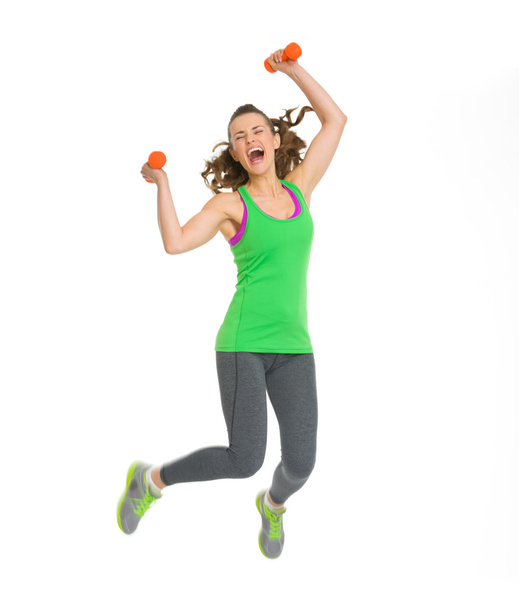 Happy fitness young woman with dumbbells jumping - Foto, imagen