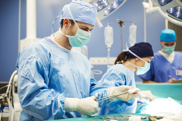 Хирург с помощью медицинских ножниц во время операции
 - Фото, изображение