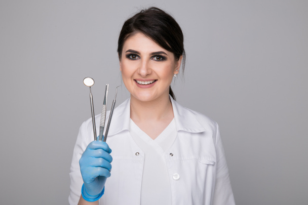 Dentista femenina con herramientas en gris
 - Foto, Imagen