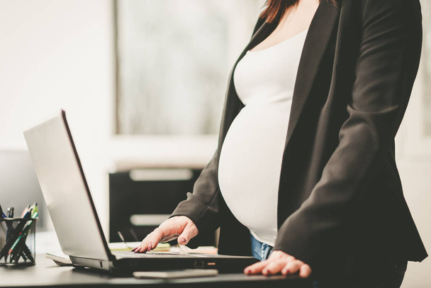 Mulher grávida trabalhando no laptop no escritório
 - Foto, Imagem