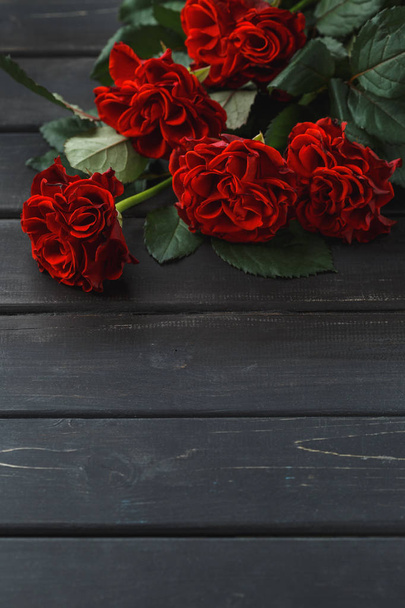 Red roses flowers over black wooden background - Photo, Image