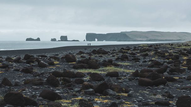 Couple of people walking at the empty Reynisfjara black beach in Iceland - Foto, Bild