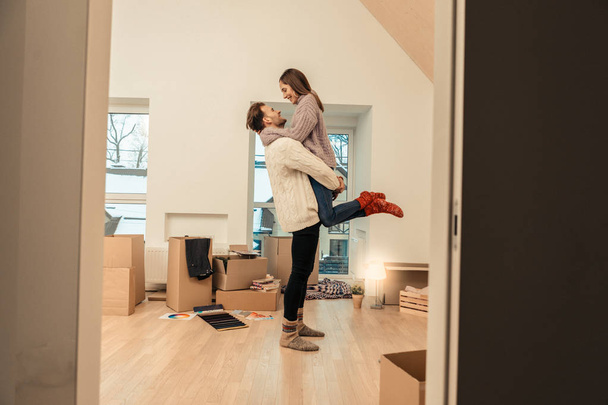 Happy couple standing in the middle of room with many boxes - Photo, image