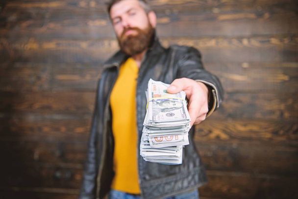 Illegal profit and black cash. Guy mafia dealer with cash profit. Man give cash money bribe. Richness and wellbeing. Mafia business. Man brutal bearded hipster wear leather jacket and hold cash money - Photo, image