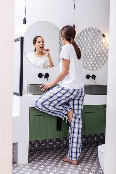 Woman wearing comfy baggy pajamas brushing teeth in the morning - Fotó, kép