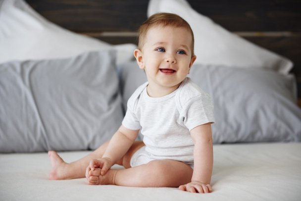 Smiling baby sitting on bed - Foto, afbeelding
