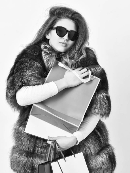Discount and sale. Buy with discount on black friday. Shopping with promo code. Woman shopping luxury boutique. Girl wear sunglasses and fur coat shopping white background. Lady hold shopping bags - Foto, afbeelding