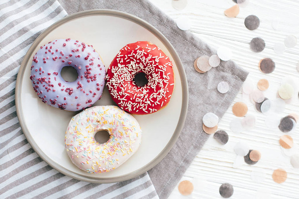 Delicious colorful donuts with sprinkles on stylish plate on whi - Фото, зображення