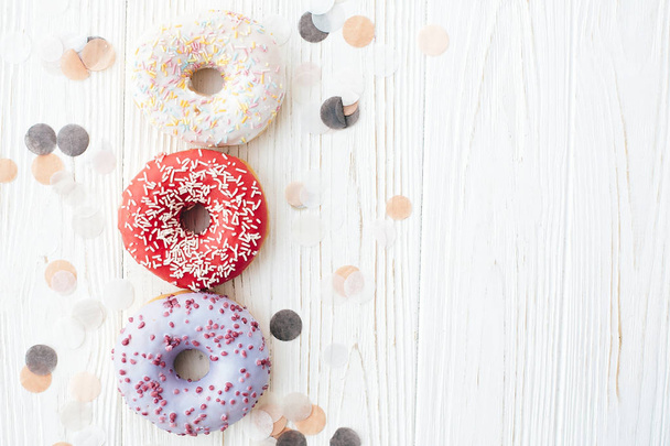 köstliche bunte Donuts mit Streusel auf stilvollem weißen Tisch - Foto, Bild