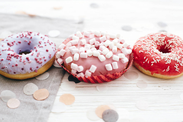 Delicious colorful donuts with sprinkles and marshmallows on sty - Фото, зображення