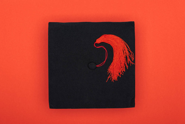 Top view of academic cap with tassel on red surface - Photo, Image