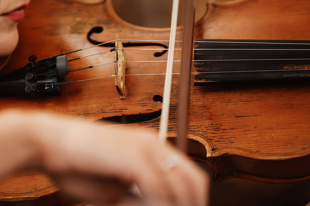 Nahaufnahme einer Geige mit Bogen. braune Orchestergeige. Finger auf der Violintastatur. - Foto, Bild