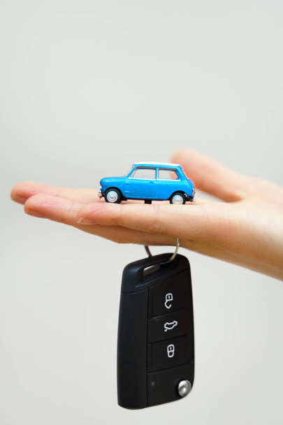 Hand holding small car toy and keys. Car purchase concept. - Photo, Image