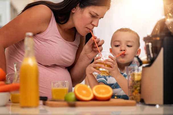 Mother and her little son having fun while making juice together. - Photo, Image